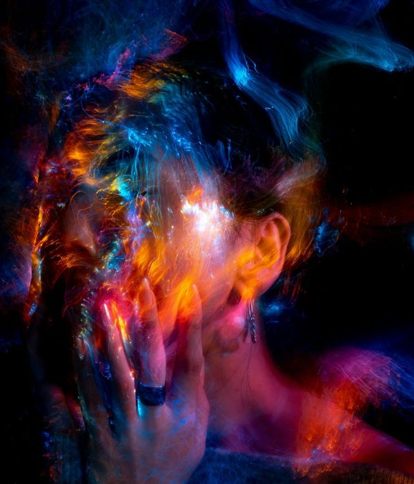 Woman in a calm, balanced pose against a dark background with light blue energy lines.